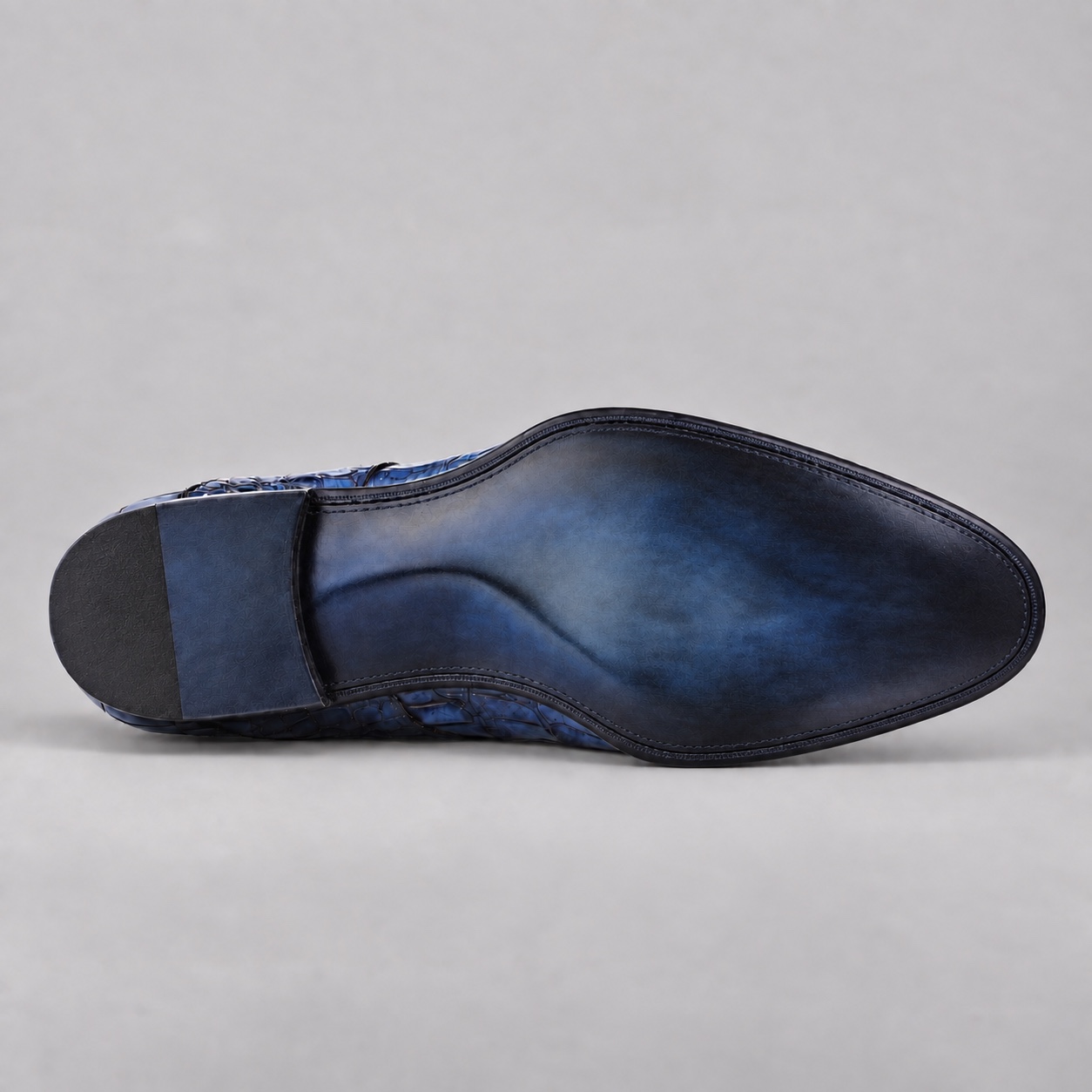 Underside of blue alligator double monk strap shoe with a clean navy-charcoal burnished sole and dark heel
