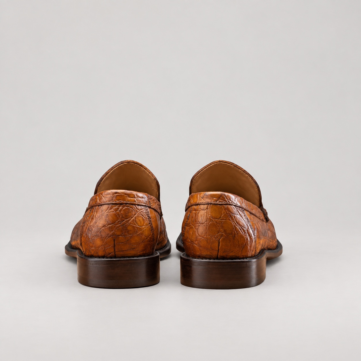 Rear view of mahogany alligator slip-on loafers showing heel seams and brown sole edges