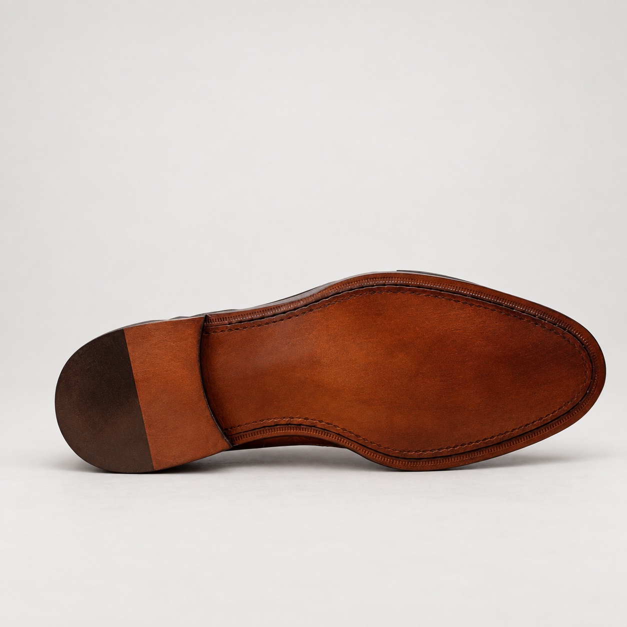 Unbranded brown patina outsole preview with perimeter stitching and a dark heel section