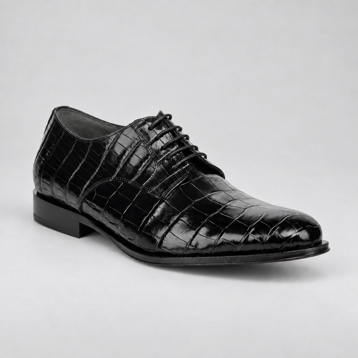 Three-quarter view showing glossy black alligator scales and dark grey cow suede lining