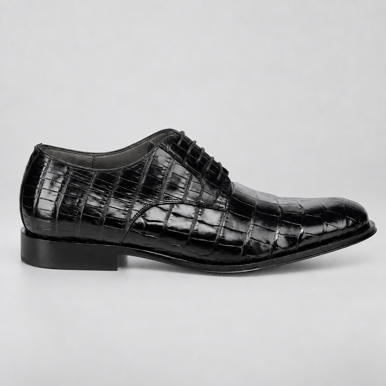 Outer side of a black alligator lace-up shoe with a near-black sole edge