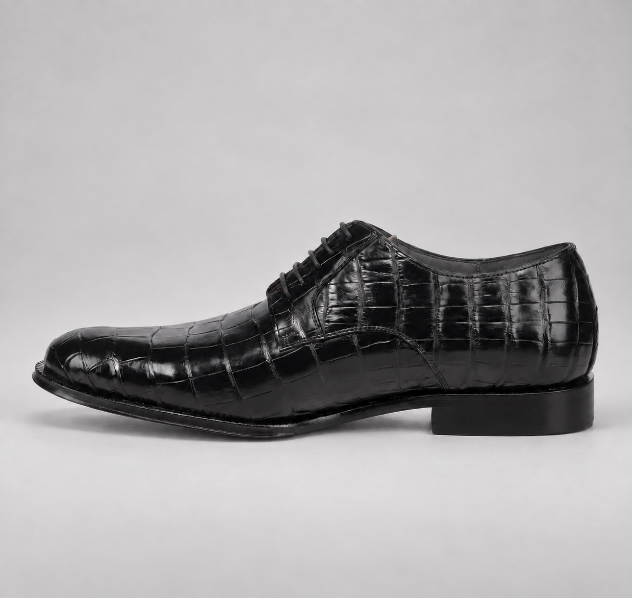 Inner side profile of a polished black alligator lace-up shoe