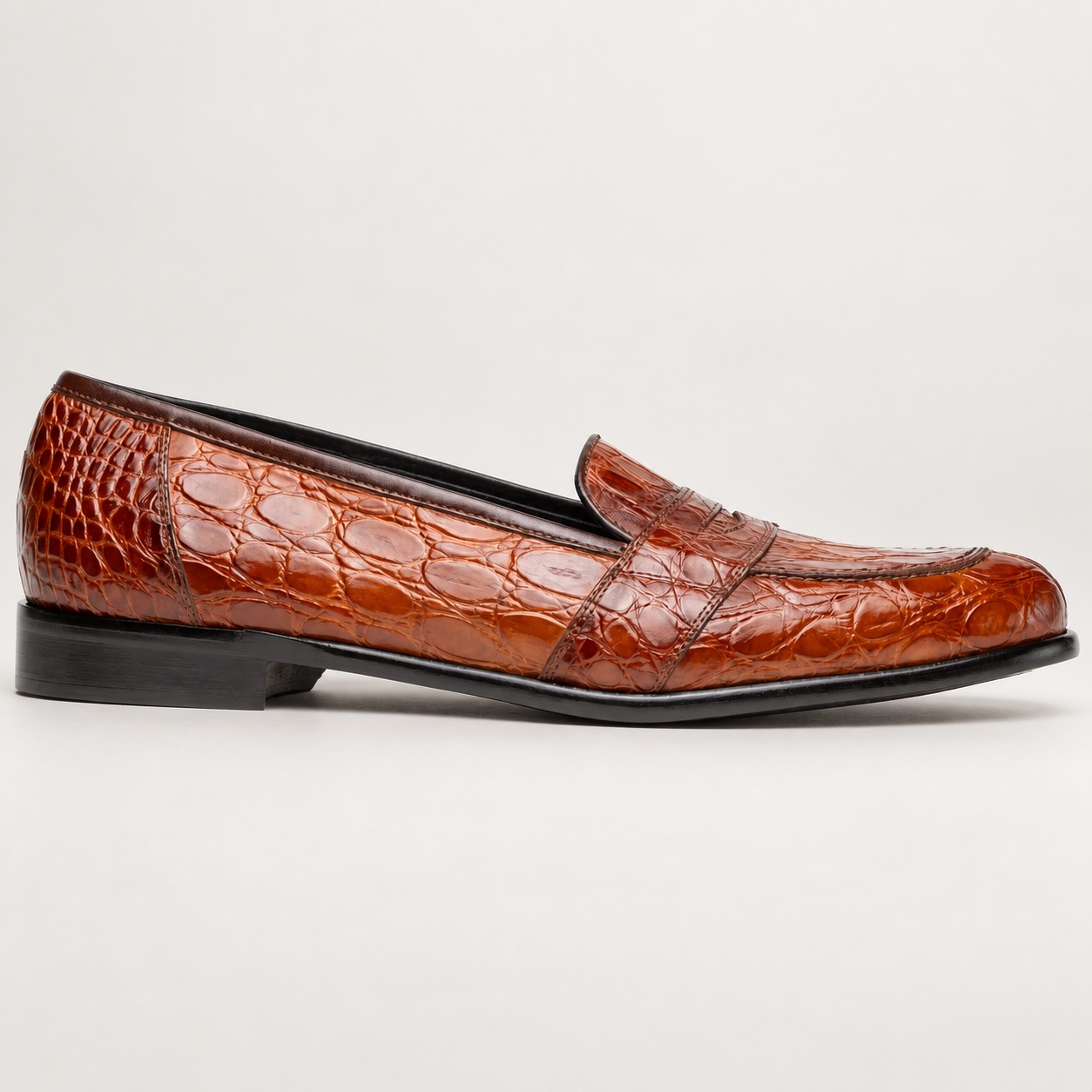 Side view of the cognac crocodile penny loafer and low heel