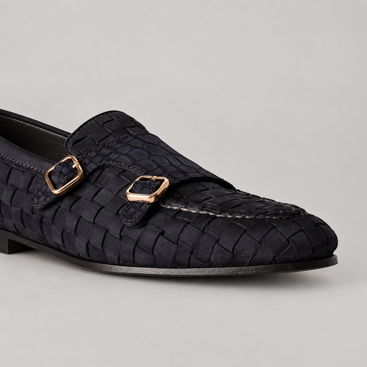 Close-up of woven suede, alligator leather panel and gold-tone buckles