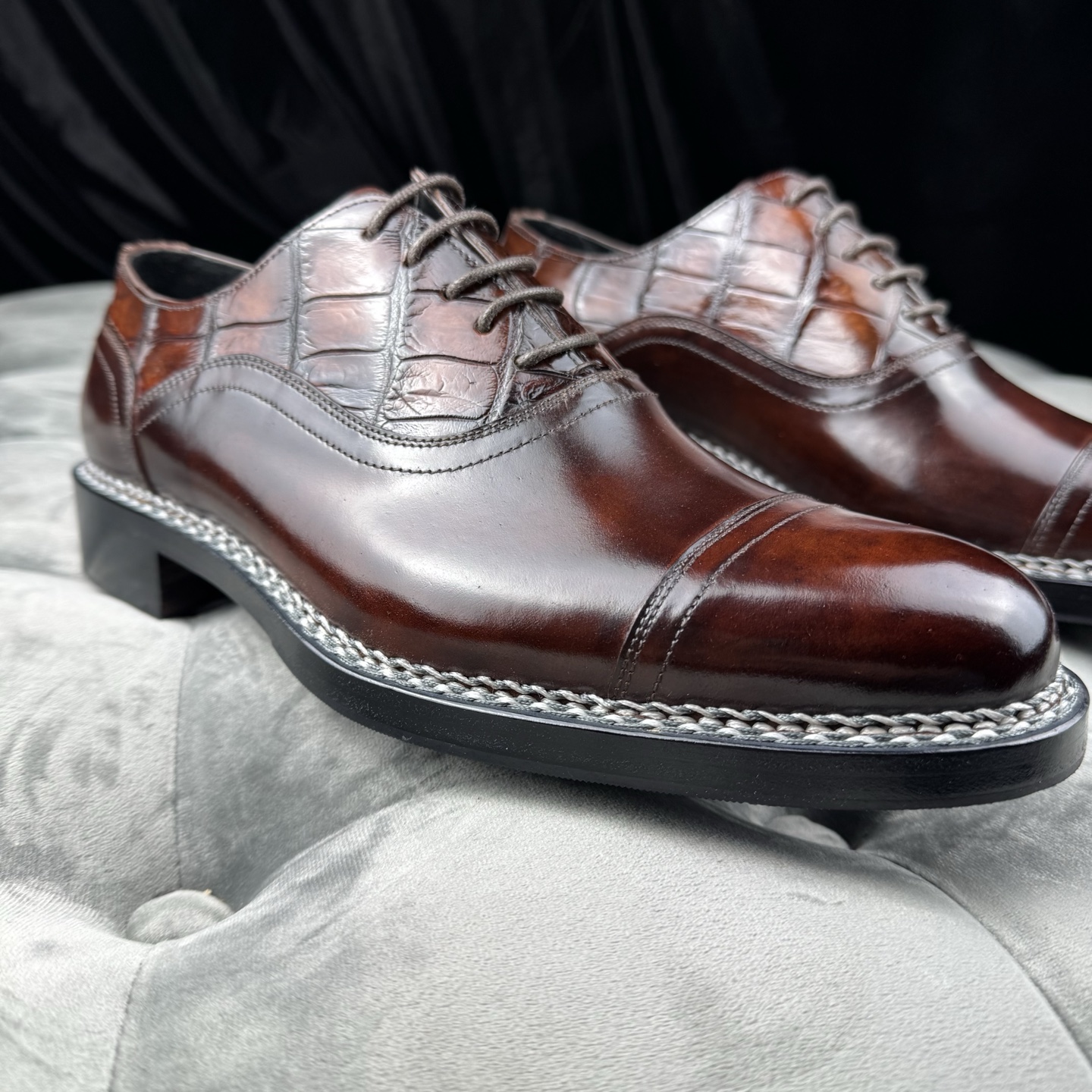 Close side view of brown lace-up dress shoes showing the toe cap, quarter, lacing area, and sole edge