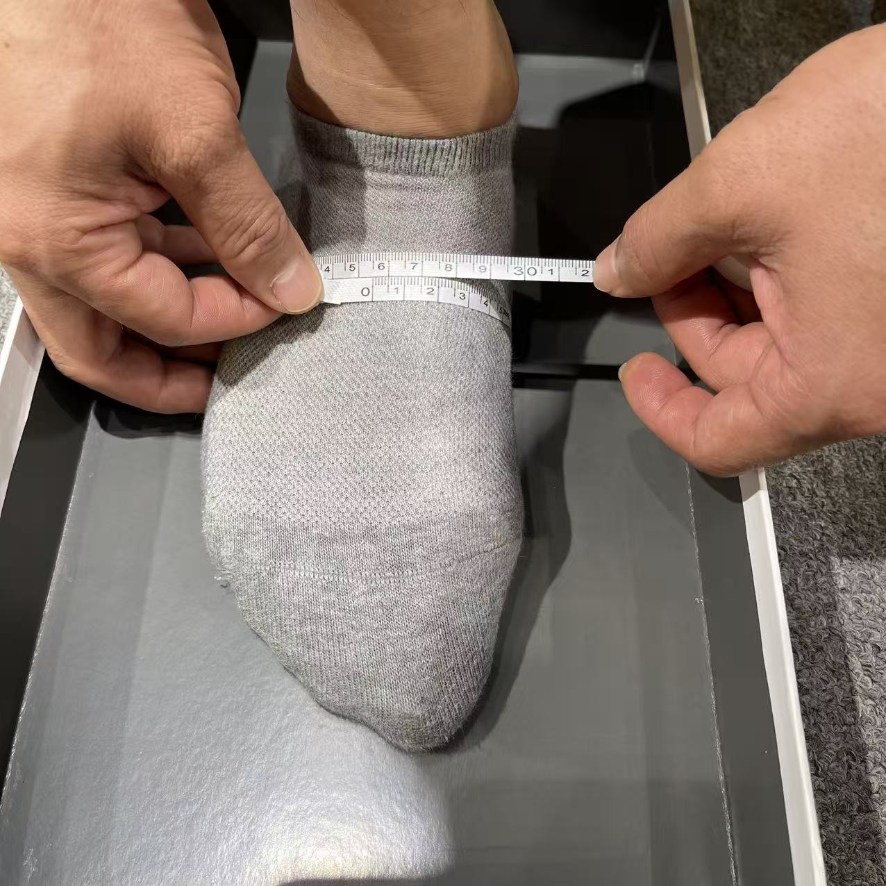 Measuring tape held level around the ball of the foot without twisting